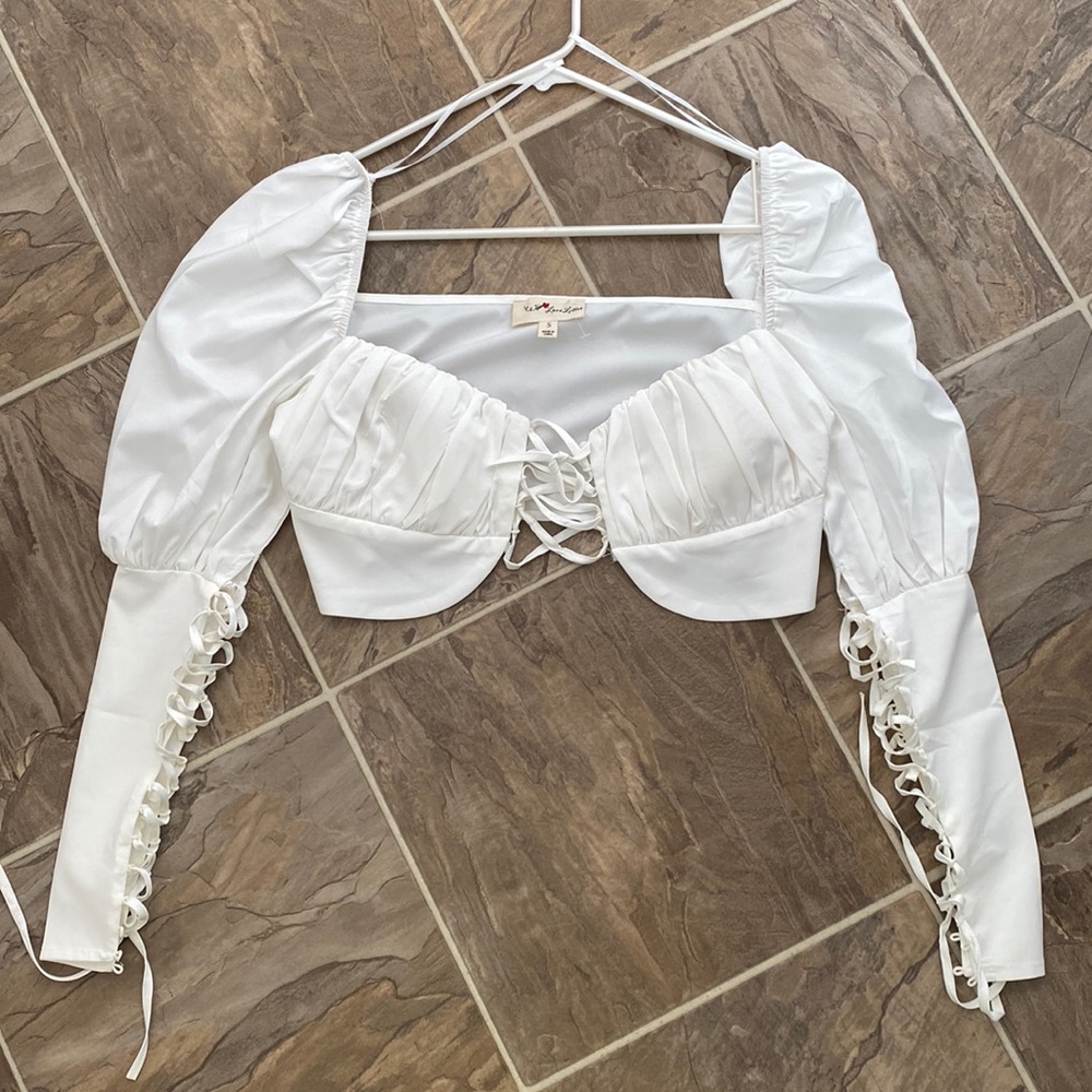 White top with puffy sleeves and lace up detail.